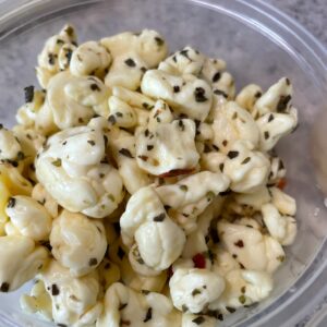 A bowl of freshly made cheese curds that are flavored with roasted red pepper flakes.