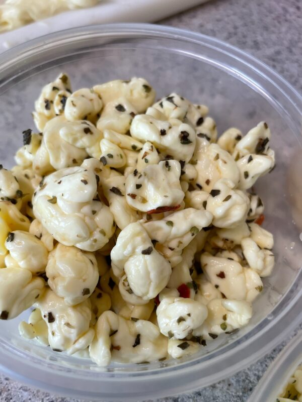 A bowl of freshly made cheese curds that are flavored with roasted red pepper flakes.