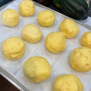 A tray that is full of 1/2 cup sized yellow butter balls.